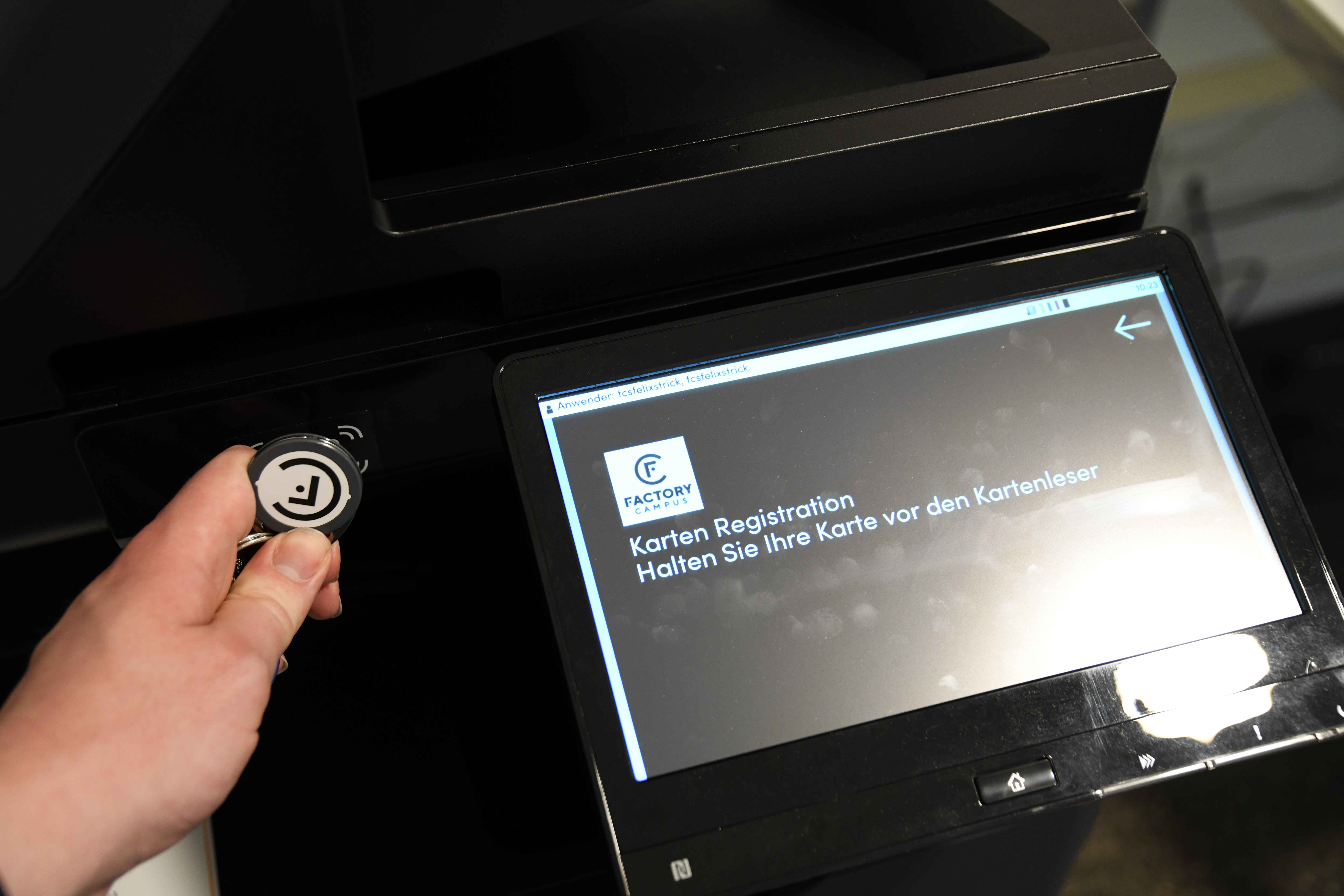 Hand die auf die Stelle am Drucker zeigt an der Transponder vorgehalten werden müssen